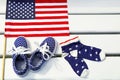 American flag, children's sneakers, socks on white wooden background. Royalty Free Stock Photo